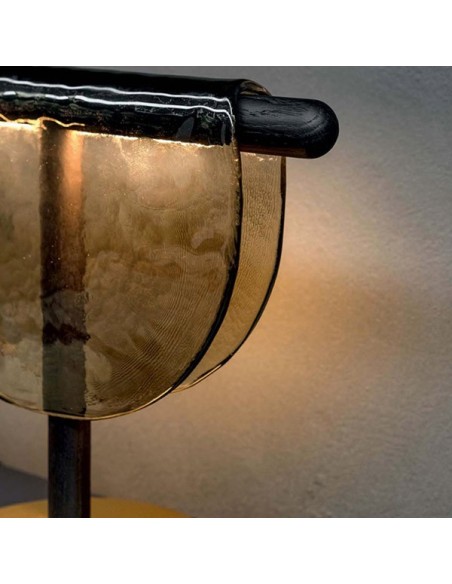 Lámpara de vidrio fundido sobre una estructura de madera y base de metal.