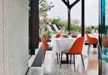 Ambiente de restauración con sillas Lea tapizadas por delante en gris y por detrás en naranja