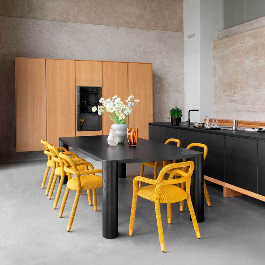 Ambiente de comedor-cocina con mesa Eggen en color negro y sillas Pippi en color amarillo