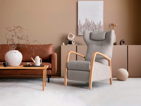 Ambiente de salón con sillón Edén tapizado en tela color gris con reposabrazos de madera de haya