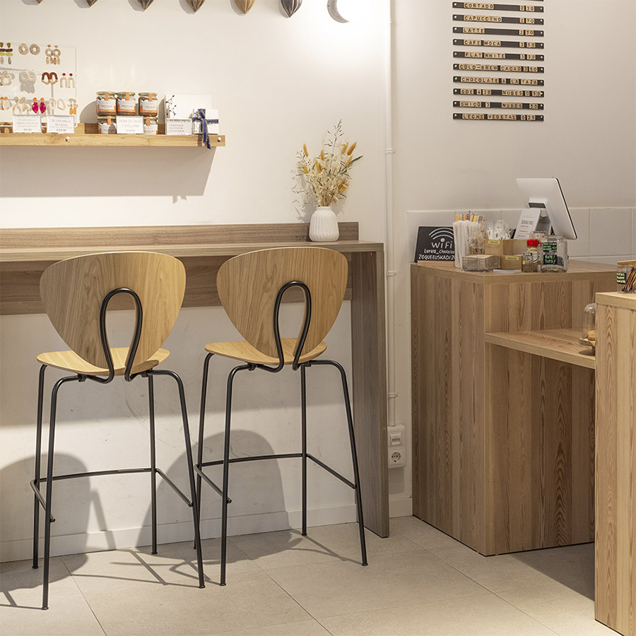 Taburete Globus de Stua de asiento madera y estructura acero con vista trasera en ambiente cafetería