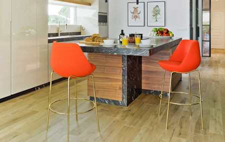 Ambiente de cocina con dos taburetes Magnum con patas doradas y tapizado en tela naranja