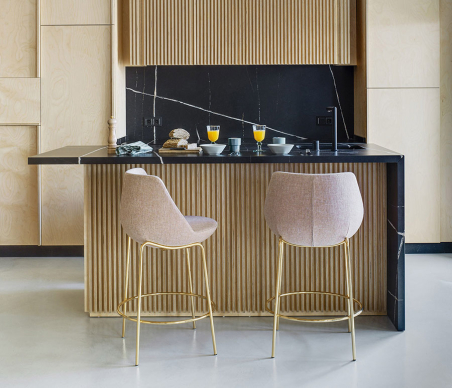 Ambiente de cocina con dos taburetes Magnum con patas doradas y tapizado en color beige