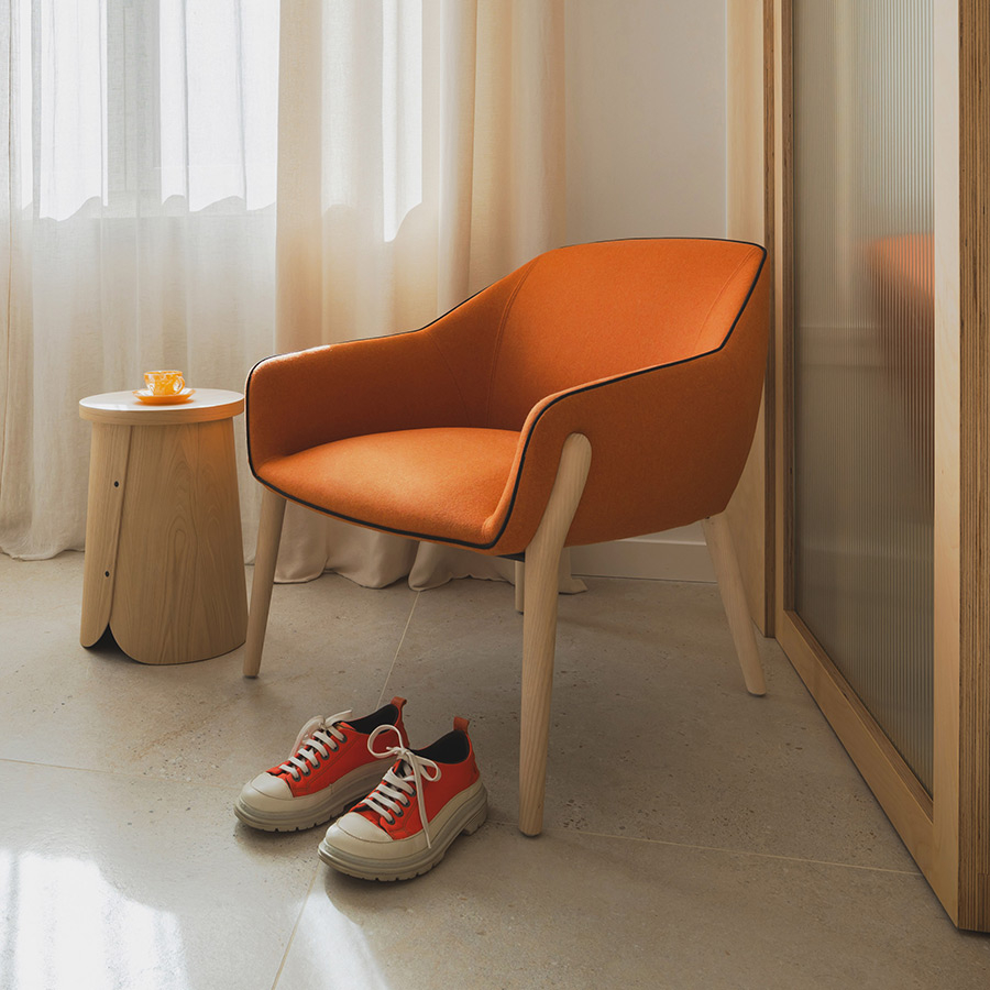 Ambiente con butaca Nido de Sancal con patas de madera y tapizado en color caldera