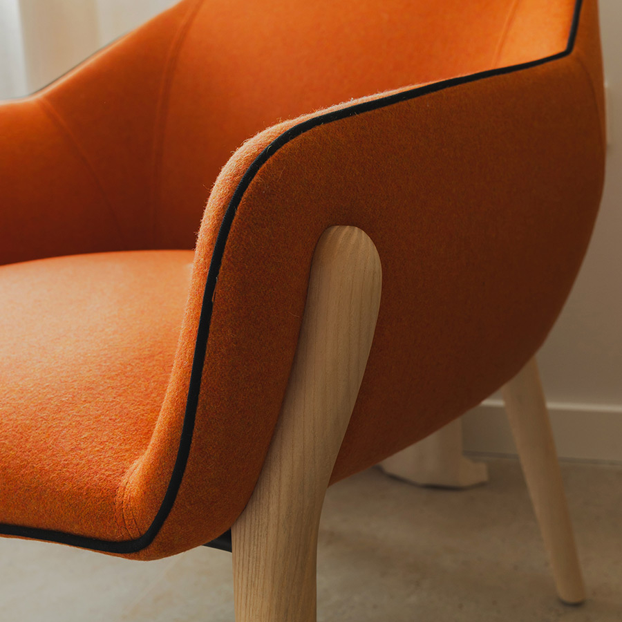 Detalle de la butaca Nido de Sancal con patas de madera y tapizado en color caldera