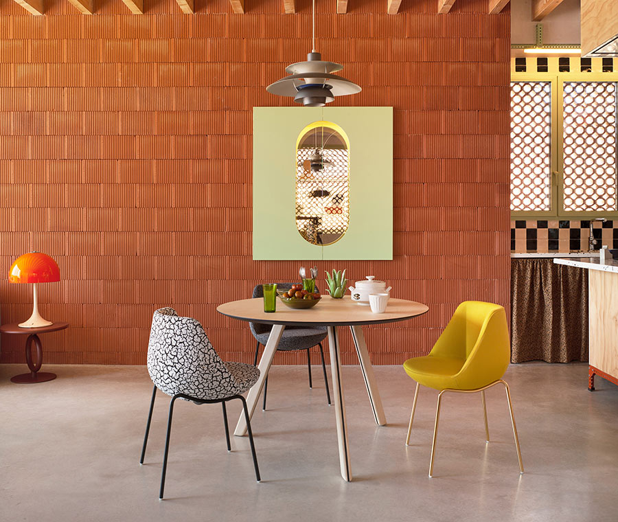 Ambiente de comedor con dos sillas Magnum de Sancal con patas metálicas doradas y negras, y asiento tapizado en tela