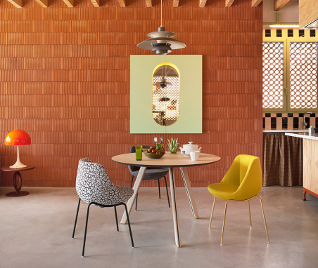 Ambiente de comedor con dos sillas Magnum de Sancal con patas metálicas doradas y negras, y asiento tapizado en tela