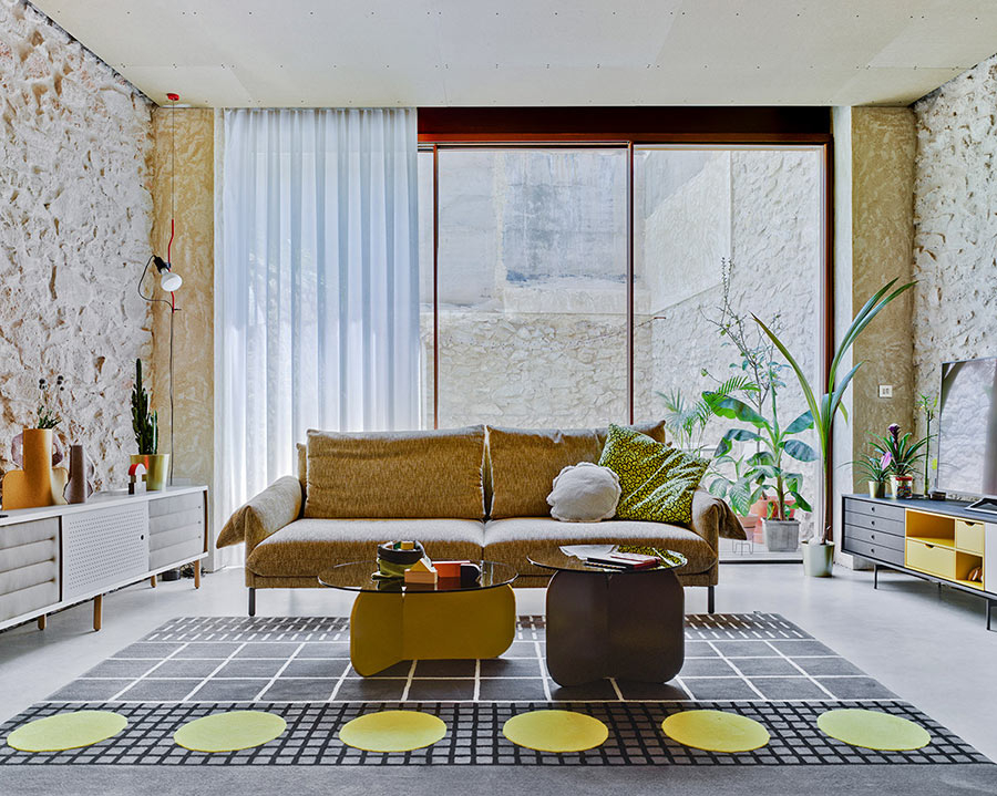 Ambiente con sofá Alpino de la firma Sancal, tapizado en tela color beige con patas en color negro