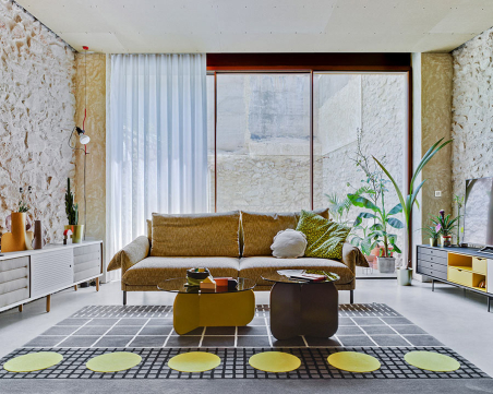 Ambiente con sofá Alpino de la firma Sancal, tapizado en tela color beige con patas en color negro