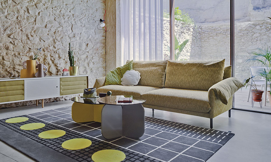 Salón con sofá Alpino de la firma Sancal, tapizado en tela color beige con patas en color negro