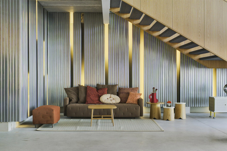 Ambiente con sofá Nap de la firma Sancal, con cojines de respaldo y tapizado en color marrón