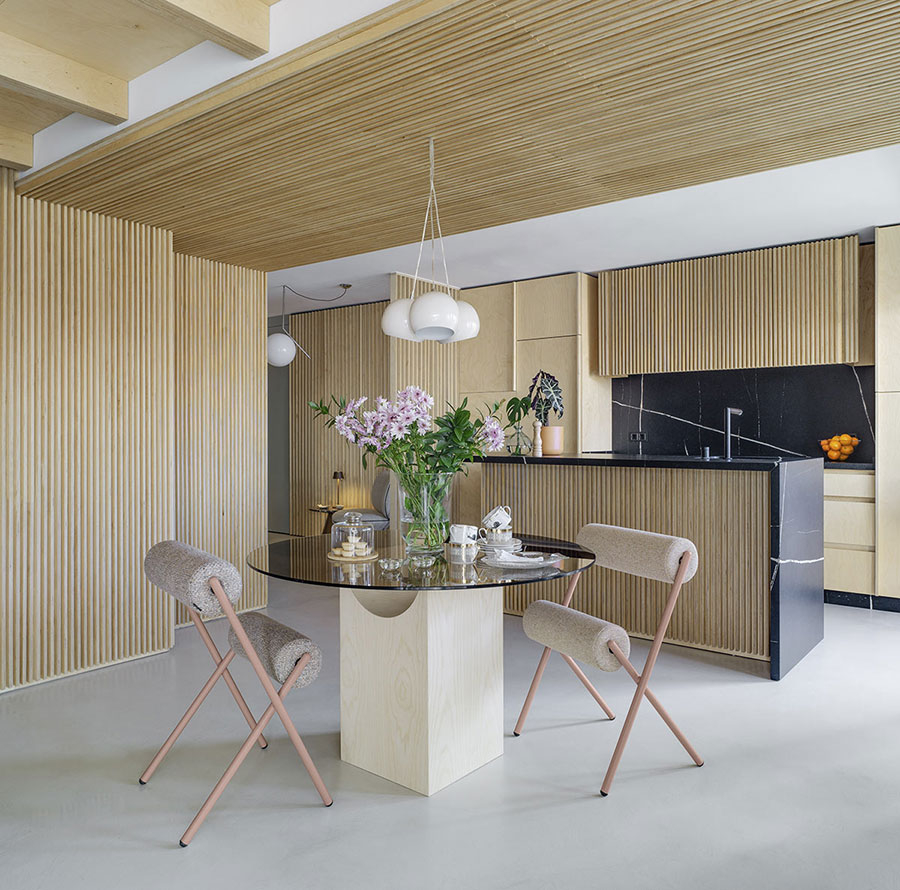 Ambiente de comedor doméstico con mesa de comedor redonda de cristal y dos sillas Roll tapizadas en tela