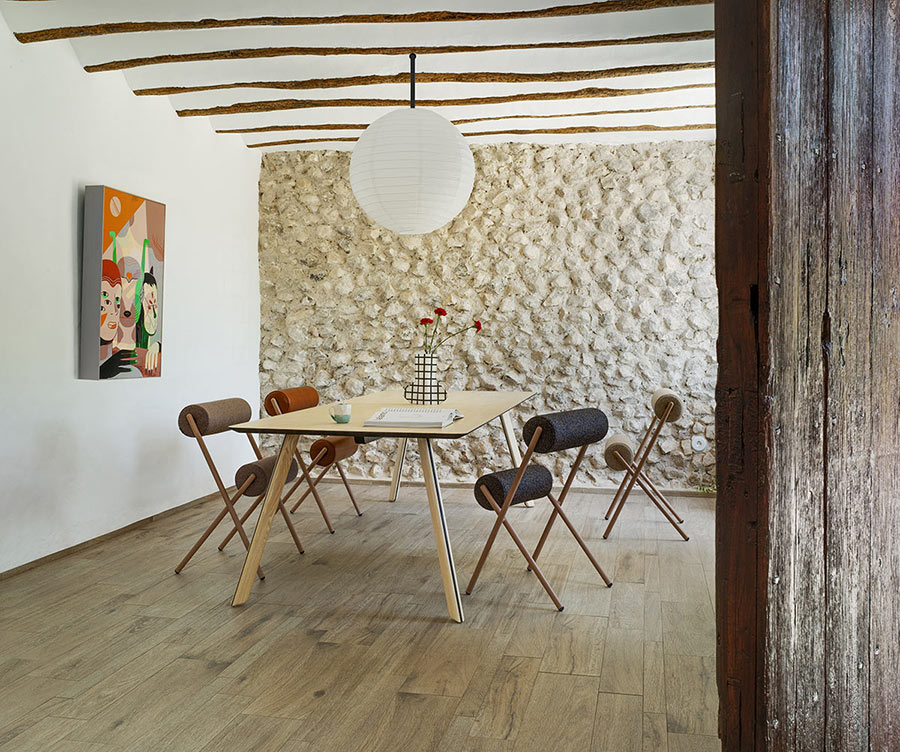 Ambiente de comedor con mesa rectangular de madera y cuatro sillas Roll tapizadas en tela