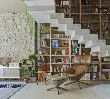Ambiente de lectura con sillón Tortuga tapizado en piel y reposapiés tapizado en tela