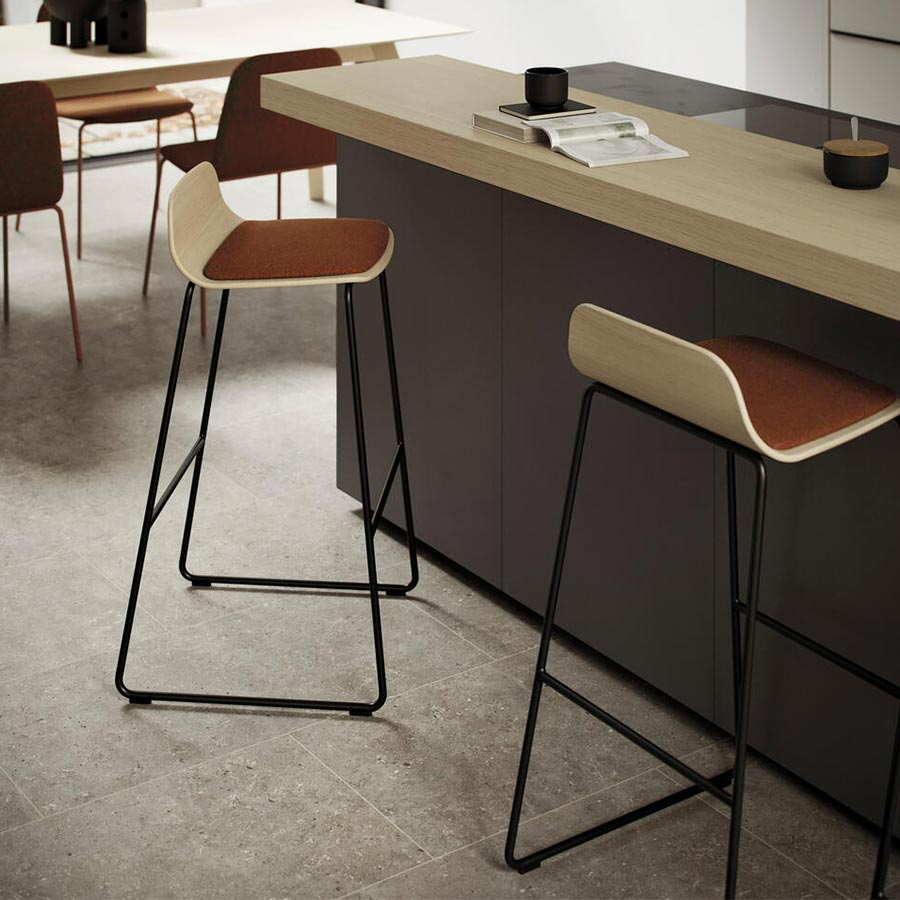 Vista ambiente del Taburete Bisell de Treku, con asiento de madera tapizado