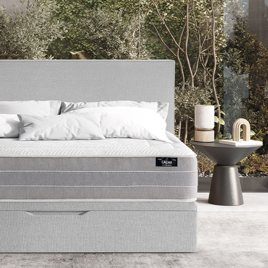 Ambiente de dormitorio con cama tapizada en gris claro y colchón Calma de la firma La Premier
