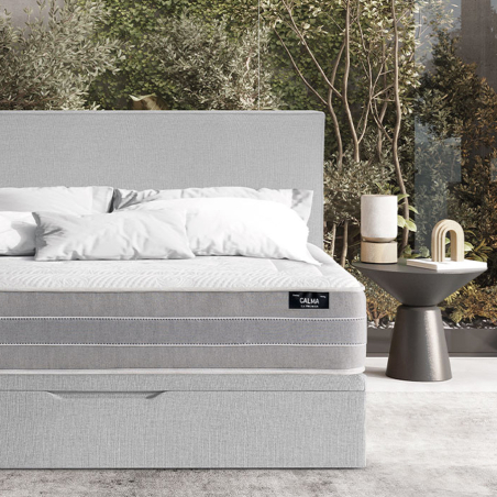Ambiente de dormitorio con cama tapizada en gris claro y colchón Calma de la firma La Premier