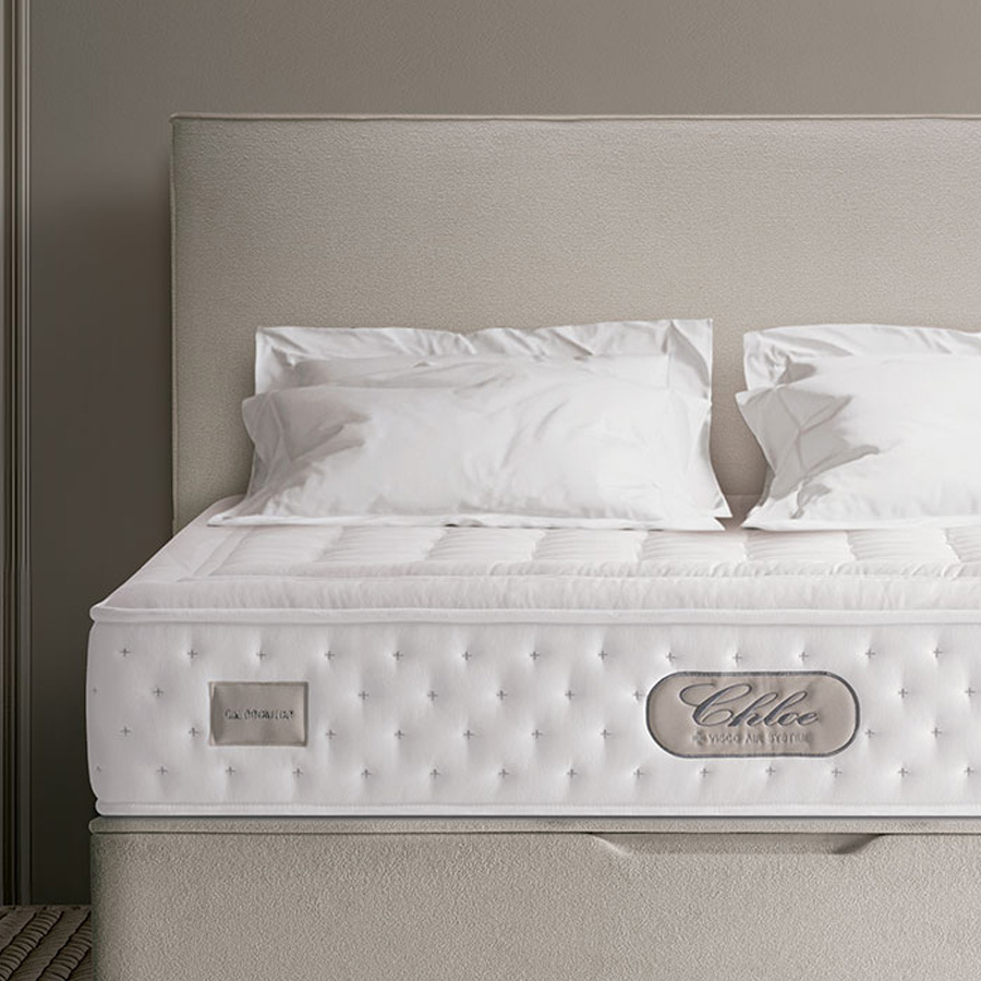 Ambiente de dormitorio con cama tapizada en color beige y colchón Chloe