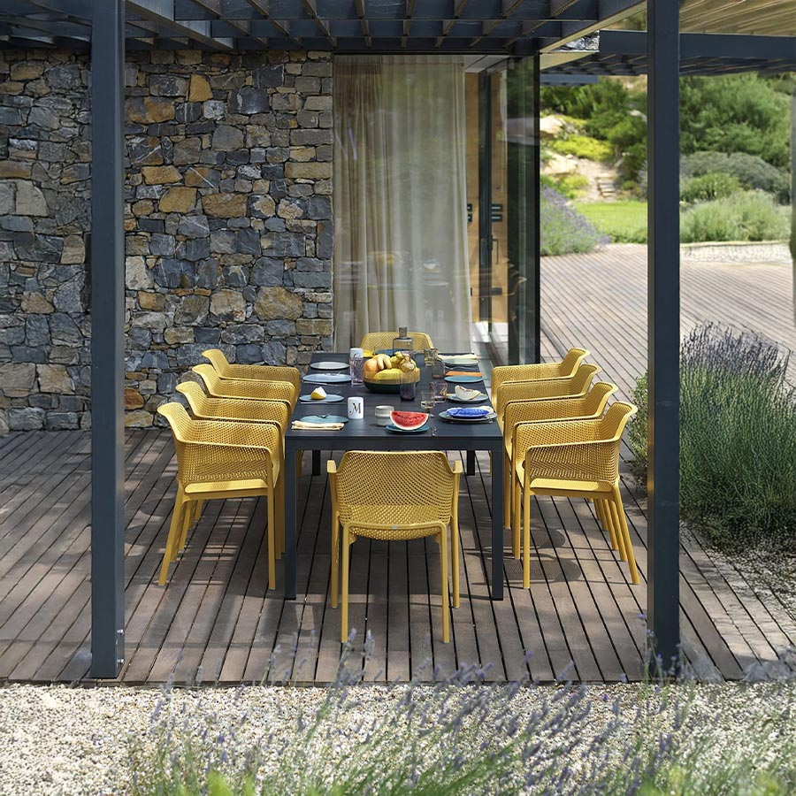 Silla de terraza Net de la firma de diseño italiana Nardi, en acabado senape y vista de ambiente.