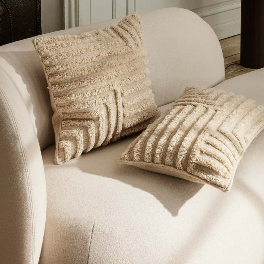 Detalle sofá Diván Rico en color blanco roto de Ferm Living en ambiente con cojines.