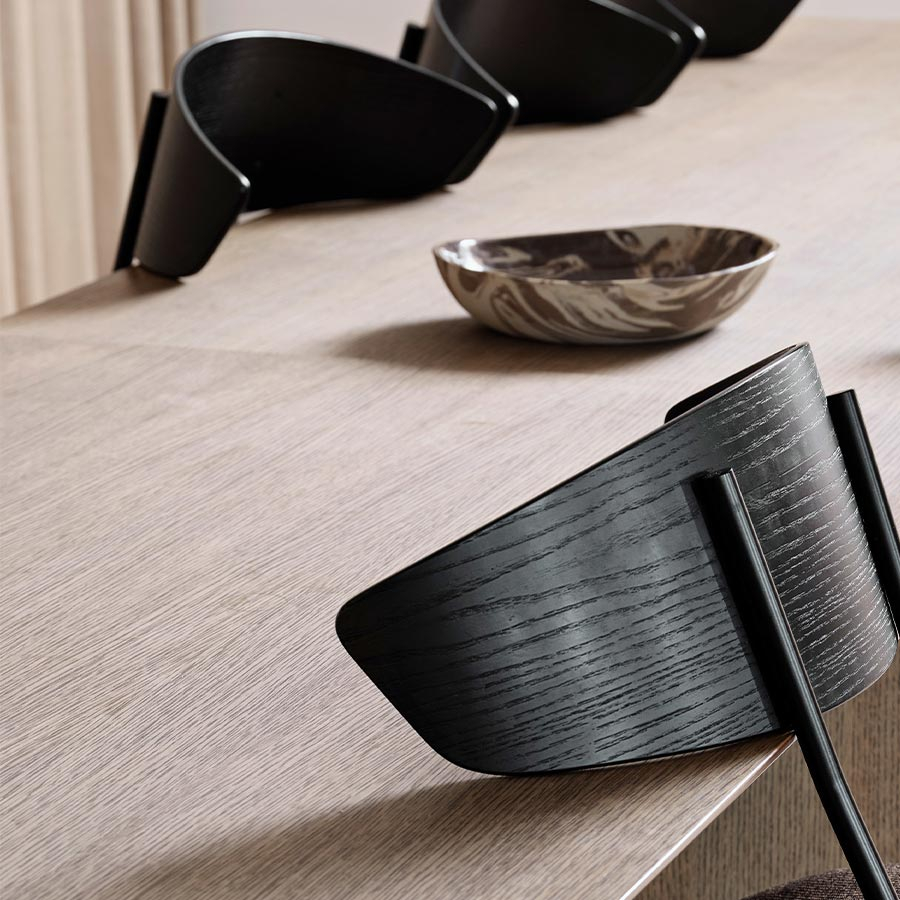 Silla Herman de Ferm Living colgada de respaldo para poder acceder mejor a limpiar bajo la mesa.