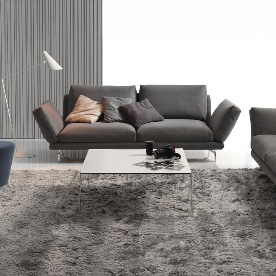 Sofá Axis de Frajumar con hueco entre almohadas, en tapizado gris oscuro y vista de ambiente.