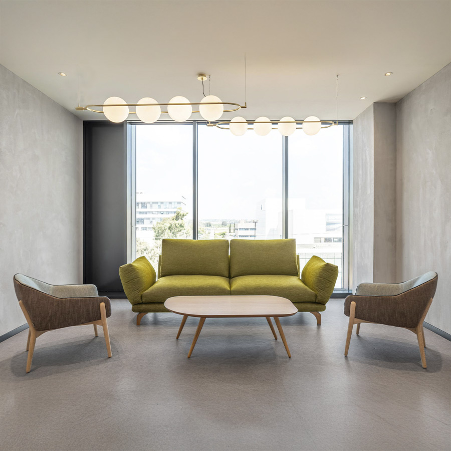 Sofá Axis de Frajumar con hueco entre almohadas, en tapizado verde y vista de ambiente.