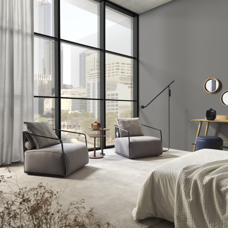 Butaca Adex de la firma Frajumar en vista de ambiente de dormitorio y tapizado gris.