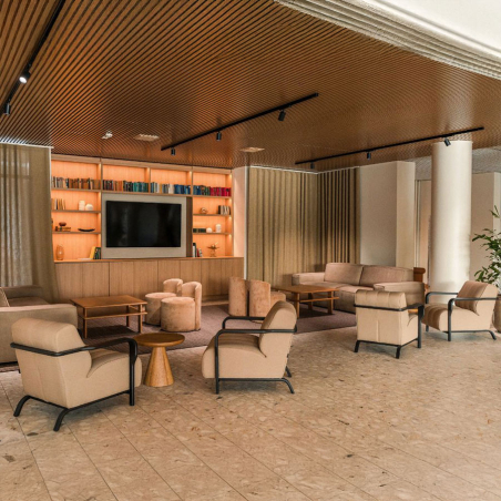 Butaca Royal de la firma Frajumar en con asiento tapizado en color crema y vista de ambiente de zona común.