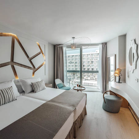 Puff Opof con respaldo y tapizado gris oscuro, en vista de ambiente de habitación de hotel.