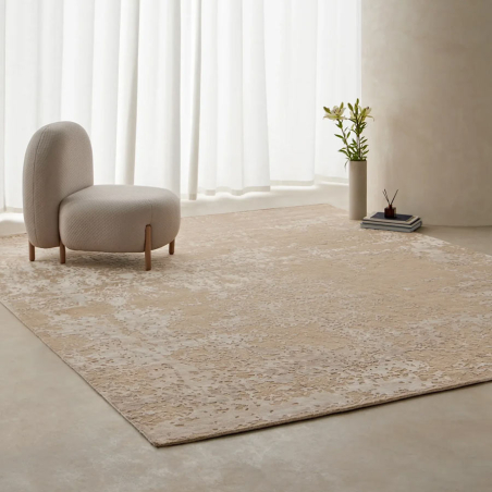 Alfombra de lujo moderno color champagne en ambiente interior relajado bajo butaca zen y jarrón minimalista.