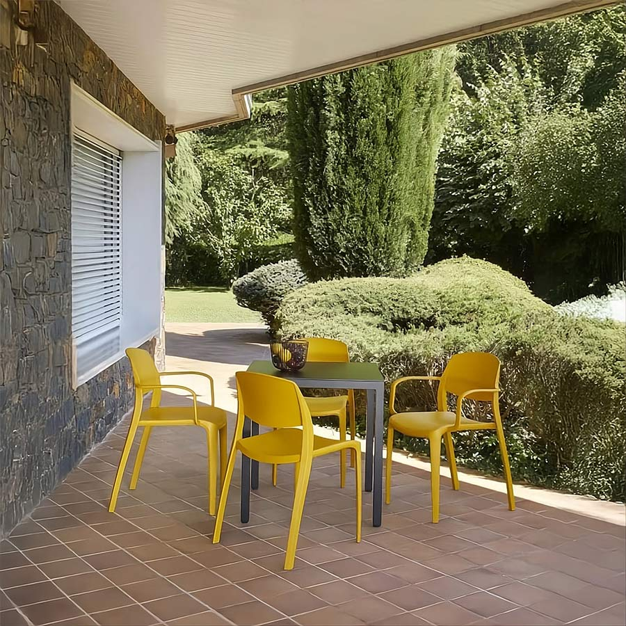 Porche en chalet con las sillas color amarillo toscano del modelo Smart de Resol alrededor de una mesa.