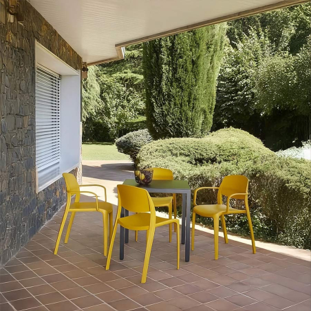 Porche en chalet con las sillas color amarillo toscano del modelo Smart de Resol alrededor de una mesa.
