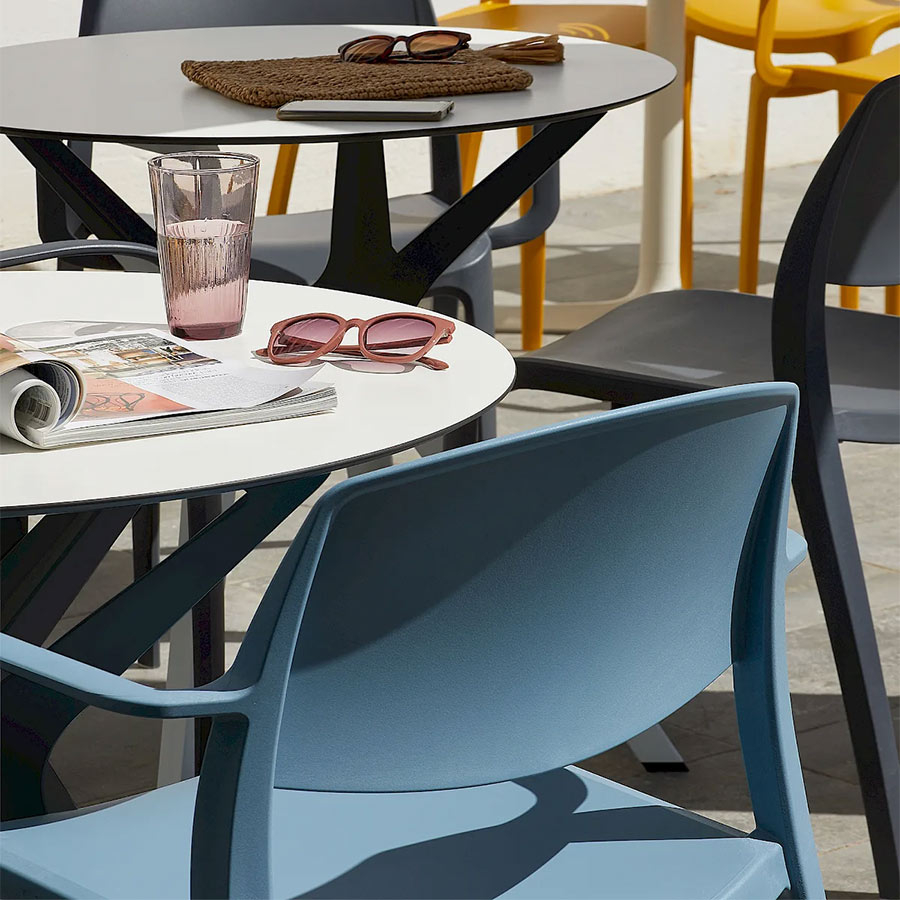 Sillas apilables de la colección Smart de diferentes colores en una terraza al sol.