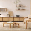 Ambiente de salón zen con muebles bajos de madera estilo Japandi: composición tv, mesas de centro redondas, alfombra grande con textura y butacas tapizadas en color crema.