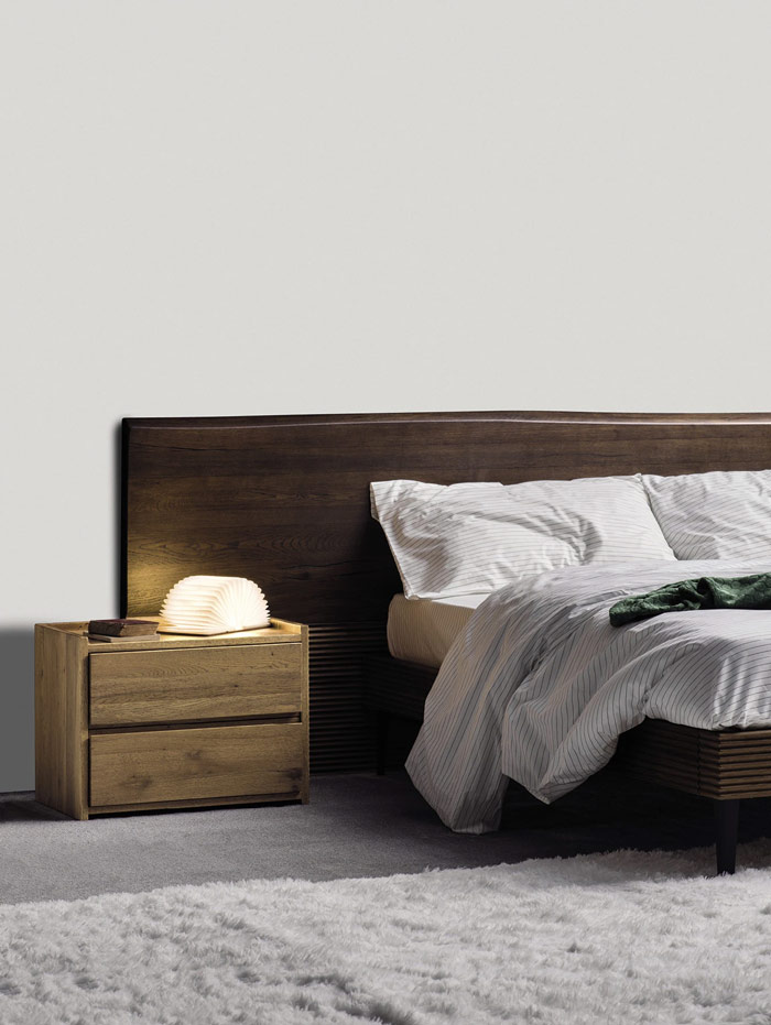 Dormitorio con cabezal de madera maciza con forma orgánica y mesita de noche de madera con dos cajones de Devina Nais.