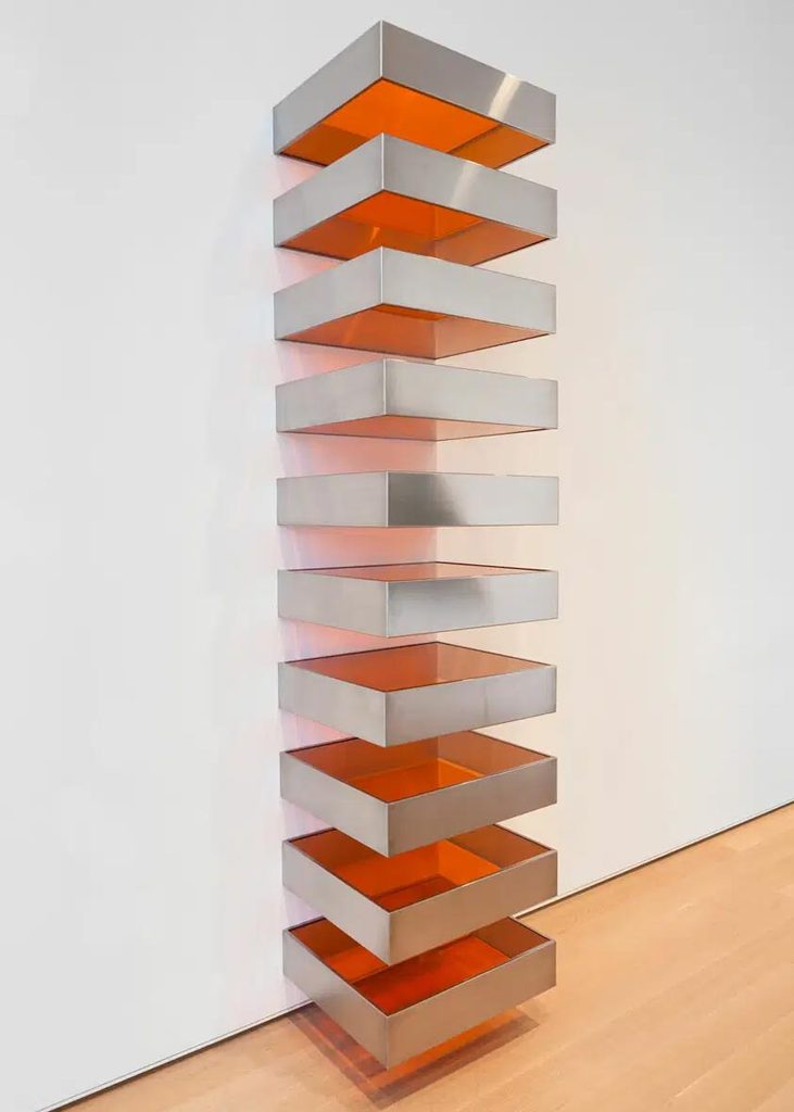 Escultura minimalista en Museo que consta de 10 piezas colocadas consecutivamente en vertical con cantos en metal y tapas en metacrilato naranja transparente.
