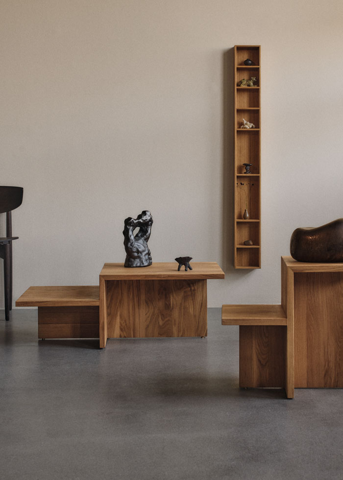 Fotografía de piezas de madera maciza de la colección Distinct de Ferm Living: mesa de centro, mesa auxiliar y estante a pared.